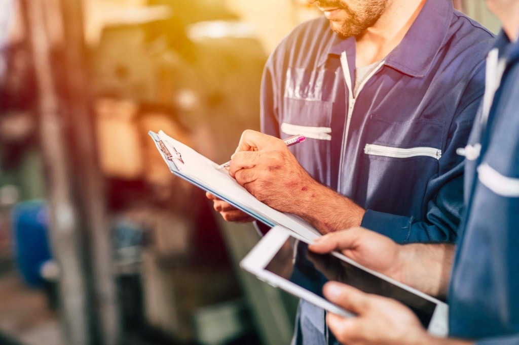 Operarios con clipboard y tablet: captura manual frente a registro digital en un TMS