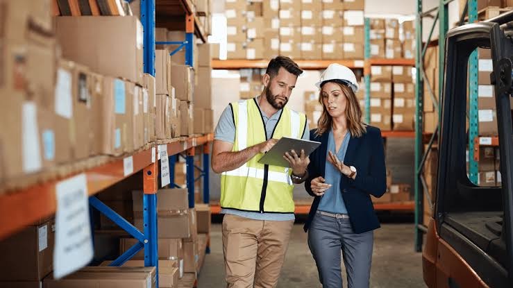 Operadores en pasillo de CEDIS revisan inventario en tablet entre racks — contexto WMS y ERP en logística México