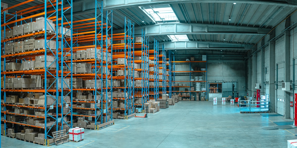 Distribution center with blue-orange racking and pallets: inventory management ready to release to a trip