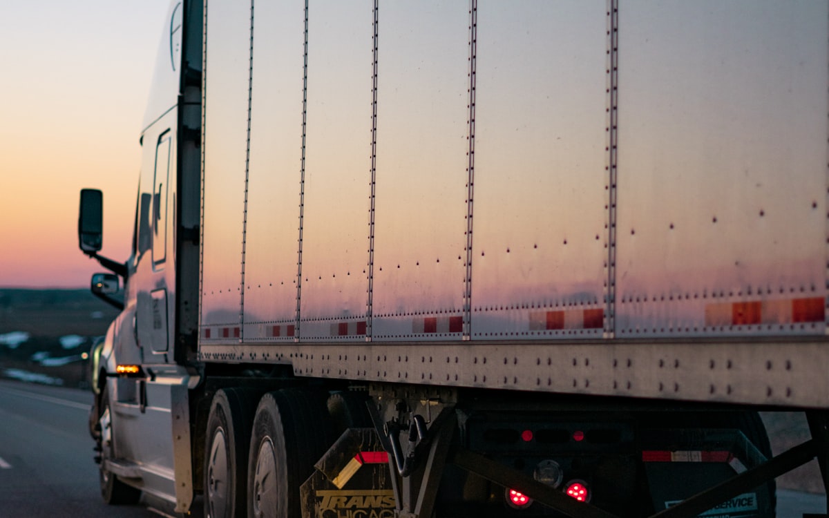 Tráiler en carretera al atardecer, visto desde atrás
